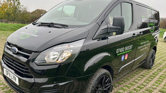 black van with company branding logo and contact information parked in a green outdoor setting showcasing mobile body shop services for five star quality repairs